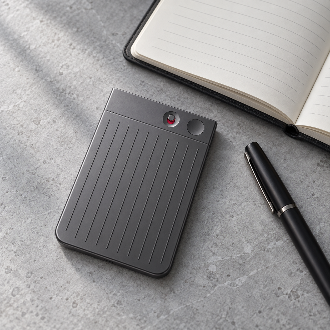 PLAUD Note recorder beside a notebook and pen.